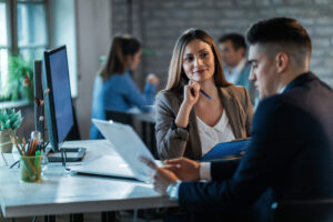 Happy businesswoman talking with a colleague while going together through paperwork.
